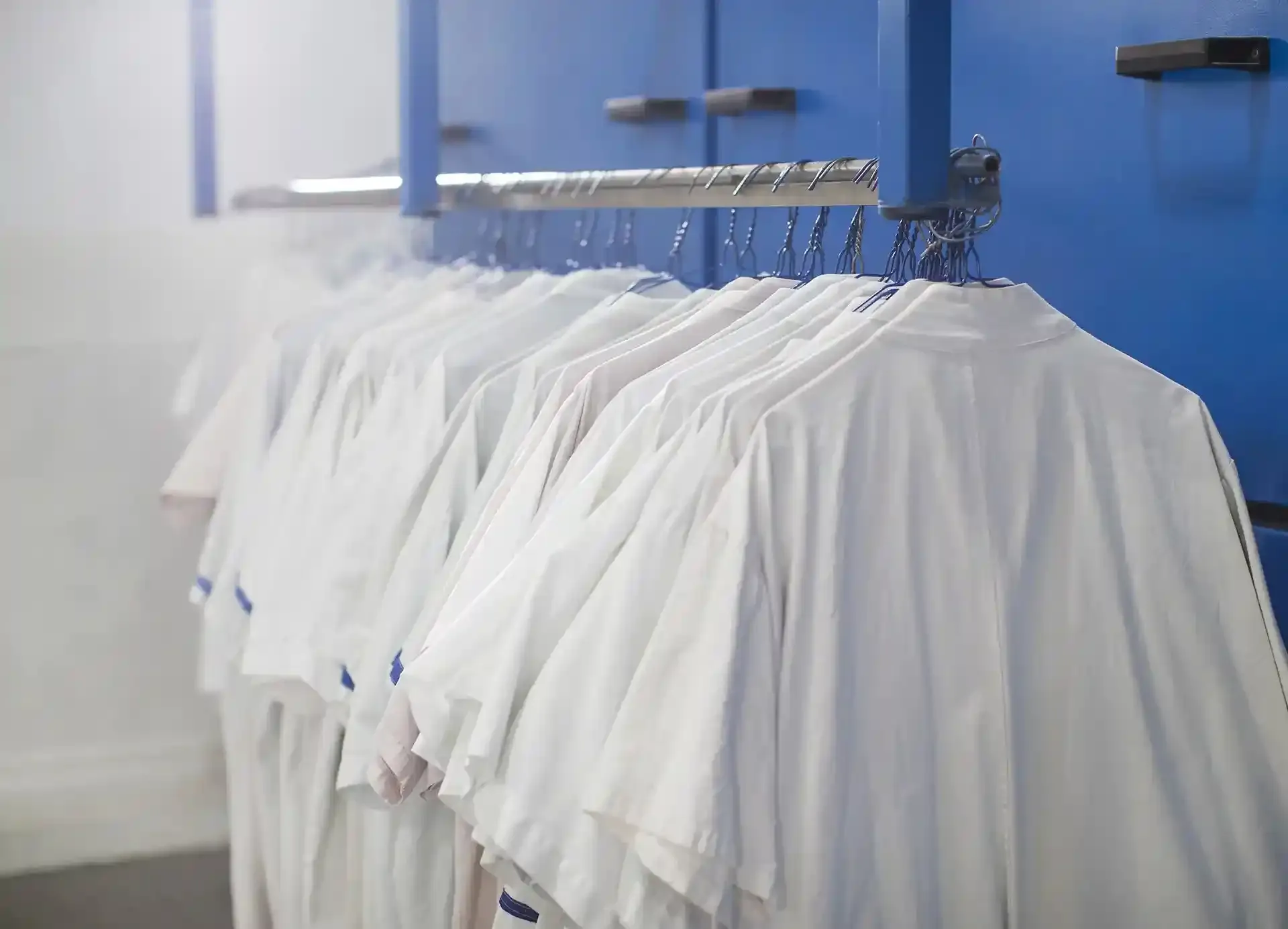 Freshly cleaned white shirts hanging on a rail.